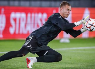Светослав Вуцов Левски оглави престижна класация Soccer goalkeeper in a black kit diving to his left, reaching for a ball near the goal line on a green pitch with red advertising boards in the background.