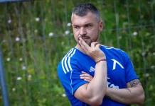 Валери Божинов с дръзка прогноза: Левски ще победи Милан в Лига Европа Man in a blue athletic shirt stands outdoors, thoughtfully resting his chin on his fingers.