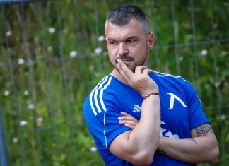 Валери Божинов с дръзка прогноза: Левски ще победи Милан в Лига Европа Man in a blue athletic shirt stands outdoors, thoughtfully resting his chin on his fingers.