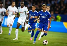 Веласкес готви промяна в атаката на Левски за НЕК Soccer player in a blue kit controls the ball while defenders in white chase him on the field.