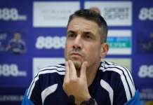 Веласкес има своя човек за „Тича“ Man in a navy sports jersey at a press conference, touching his chin with a thoughtful expression.