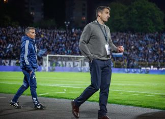 Веласкес получава важни опции обратно преди гостуването на Черно море Two men walk along a soccer field sideline during a night match; one in a gray sweater with a lanyard, the other in a blue tracksuit ahead.
