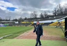 Вили Вуцов: Цяла нощ не спах след грешката на Светослав Man walking along the soccer field sideline at an empty stadium with yellow seats and a large Cyrillic banner in the stands.