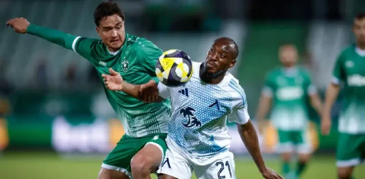 Ясни са датите за Левски – Лудогорец Soccer players vie for the ball in a tense challenge; a white-and-blue kit player shields the ball from a green-clad opponent.