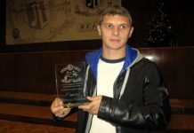 Здравко Лазаров: Левски е с крачка пред ЦСКА и Лудогорец Man in a black jacket holding a glass trophy that reads '1st place', standing on a stage indoors at an award ceremony.