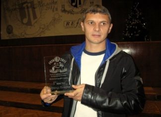 Здравко Лазаров: Левски е с крачка пред ЦСКА и Лудогорец Man in a black jacket holding a glass trophy that reads '1st place', standing on a stage indoors at an award ceremony.