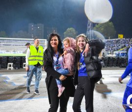 Group of three women and a child posing for a photo at a nighttime stadium during rain.